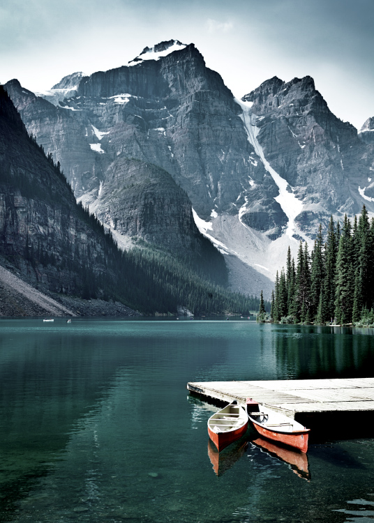  – Fotografi av en sjö med en liten brygga och två kanoter framför berg