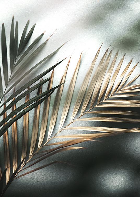  – Fotografi av två palmblad i guld och grönt på en stenbakgrund