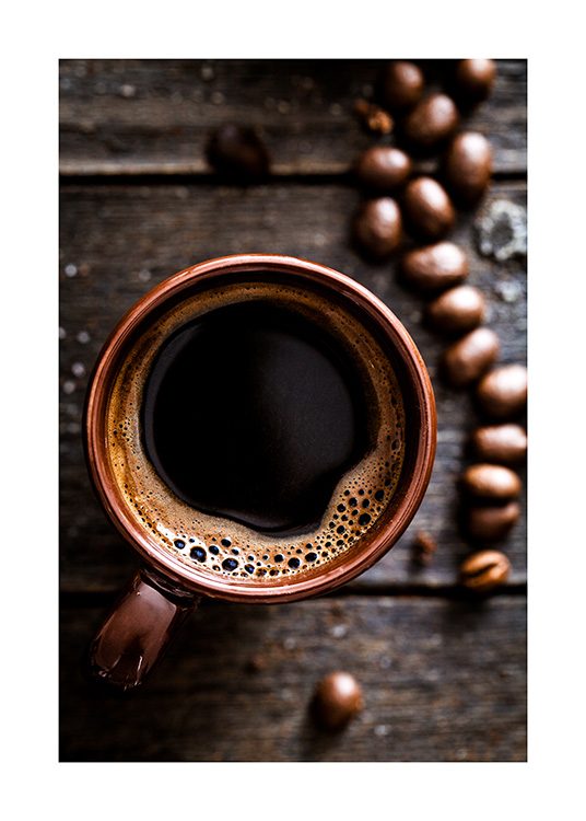  – Fotografi från ovan av en kopp kaffe på ett träbord, med kaffebönor bredvid