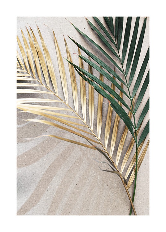  – Fotografi av två palmblad i grönt och guld som ligger på en stenbakgrund i beige