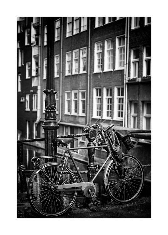 - Svartvitt fotografi av en lyktstolpe bredvid en parkerad cykel framför ett hus med fönster