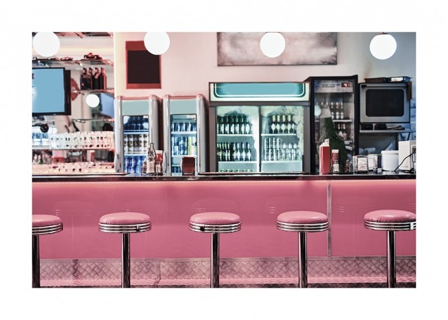 - Fotografi från en diner i retrostil med rosa barstolar framför en rosa bardisk
