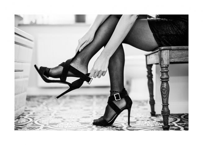 – Svartvitt foto av en kvinna som tar på sig ett par högklackade skor