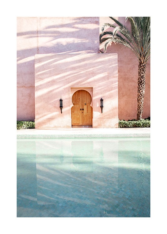  - Fotografi av en palm bredvid en rosa byggnad med en pool framför