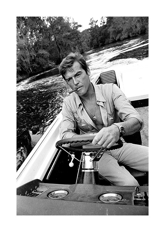  – Svartvitt fotografi av Roger Moore som kör en båt med en cigarett i munnen