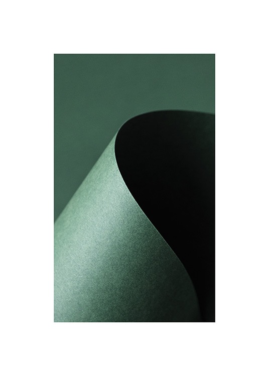  – Fotografi med närbild av ett grönt papper format till en båge, mot en mörkgrön bakgrund