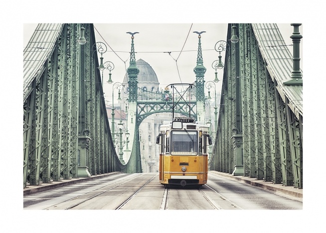  – Fotografi av en gammal, gul spårvagn på en grön bro i Budapest med byggnader i bakgrunden
