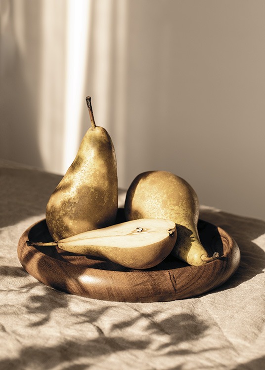  – Fotografi av tre päron som ligger i solen på en trätallrik