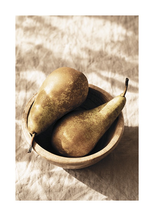  – Fotografi av två päron som ligger i en träskål på en beige linneduk