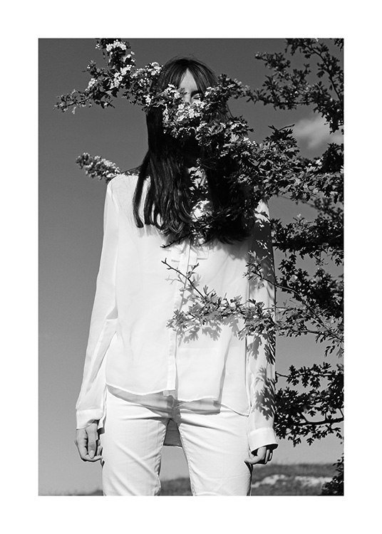 – Svartvitt fotografi av en kvinna i vita kläder, med en trädgren framför