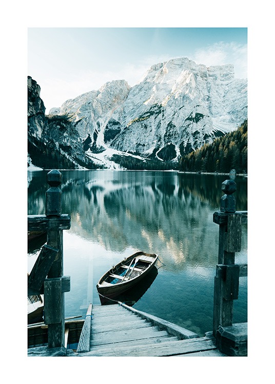  – Fotografi av snöiga berg bakom en sjö med en båt och en trätrappa i förgrunden