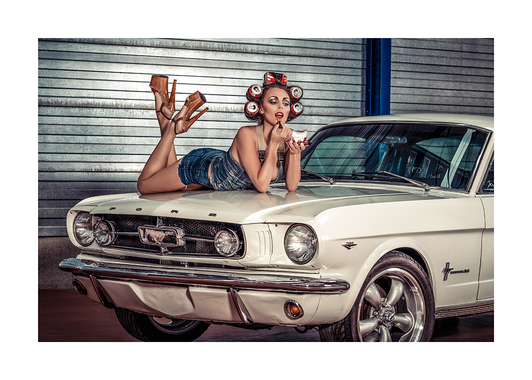  – Fotografi av en kvinna med läskburkar i håret som ligger på huven på en bil och lägger på läppstift
