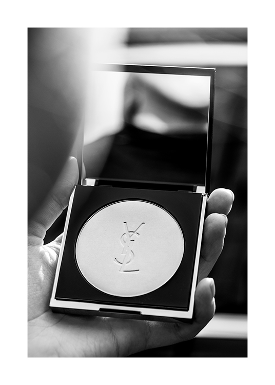  – Svartvitt fotografi av någon som håller i ett YSL-puder med en spegel