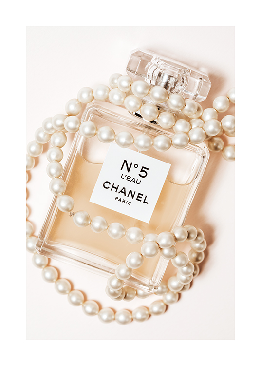  – Fotografi av en parfymflaska med Chanel No5 skrivet på den, inlindad i ett vitt pärlhalsband