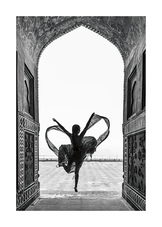  – Svartvitt fotografi av en kvinna som dansar på ett ben i en böljande klänning, inramad av att valv