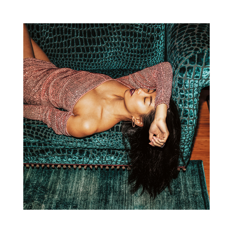  – Ett fotografi av en kvinna i en glittrande klänning som tar en tupplur på en turkos soffa
