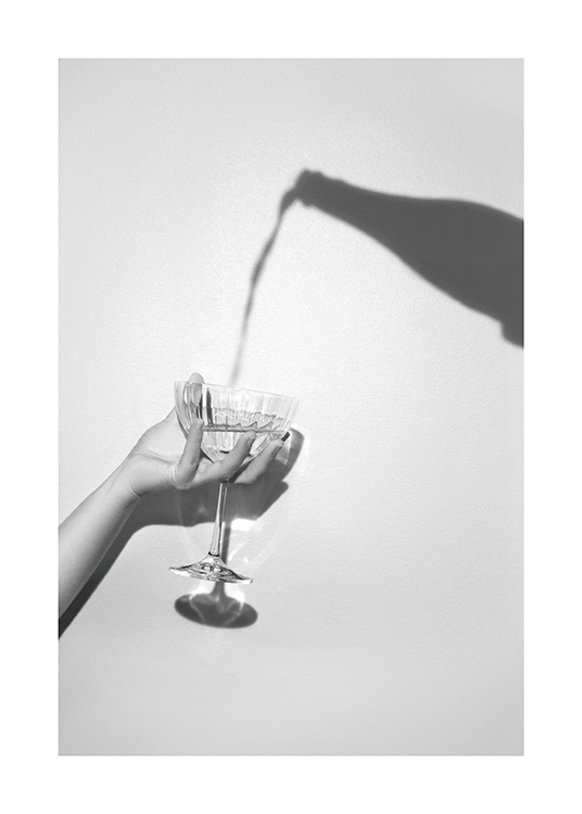  – Grått fotografi av en skugga av en champagneflaska och en hand som håller ett champagneglas