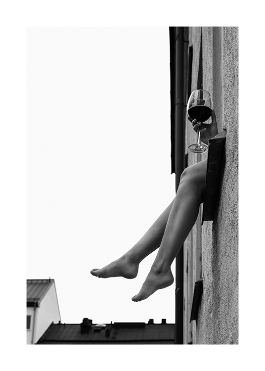  – Svartvitt fotografi av ett par ben och en hand som håller ett glas vin som sticker ut genom ett fönster