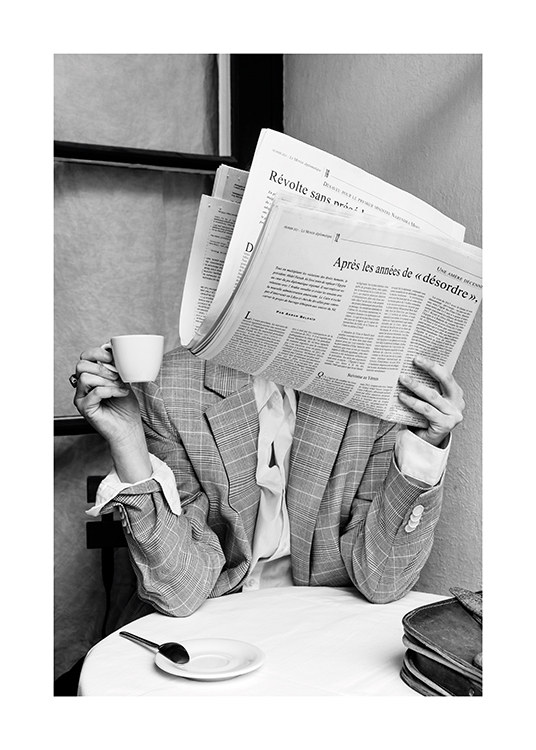  – Svartvitt fotografi av en person som sitter vid ett kafébord med en tidning som täcker ansiktet