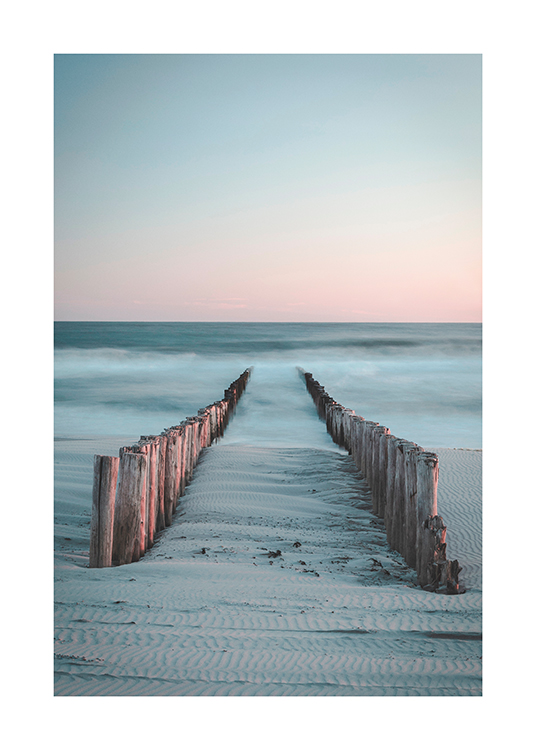  – Fotografi av två rader med träpålar som går från stranden ut till havet täckta av dimma