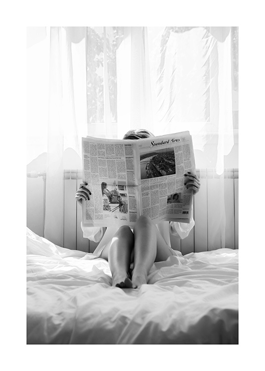  – Svartvitt fotografi av en kvinna som läser en tidning i sängen