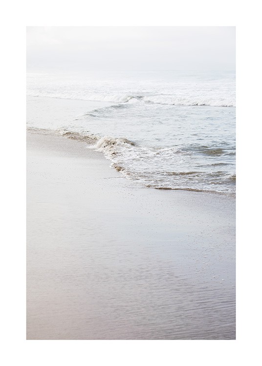  - Fotografi av en strand och en lugn strandlinje med en liten våg